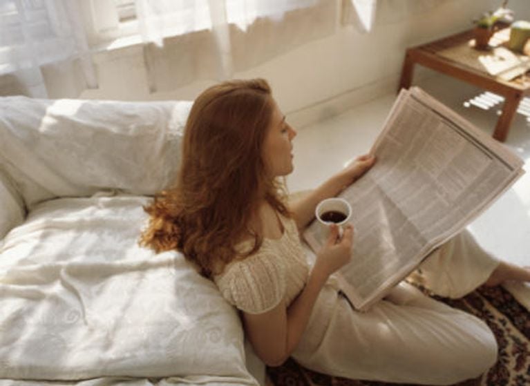 woman reading newspaper in bedroom