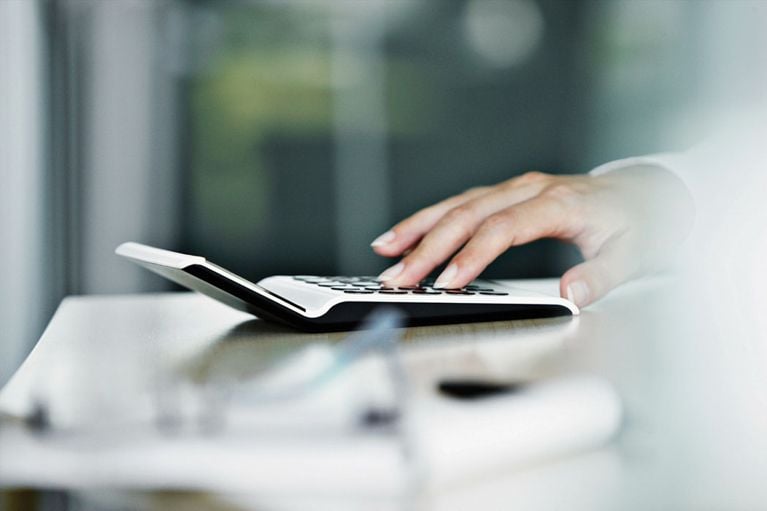 Woman calculating doing math or taxes on a calculator calculating personal finance and money