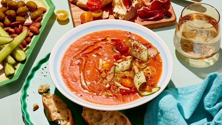 A bowl of gazpacho soup with a slice of shaved cucumber on top for a post on no-cook recipes for hot weather and also on a classic gazpacho recipe