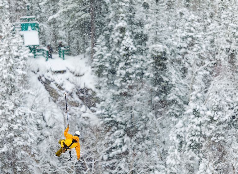 best outdoor winter activities- a man in a yellow ski jacket ziplining in newfoundland