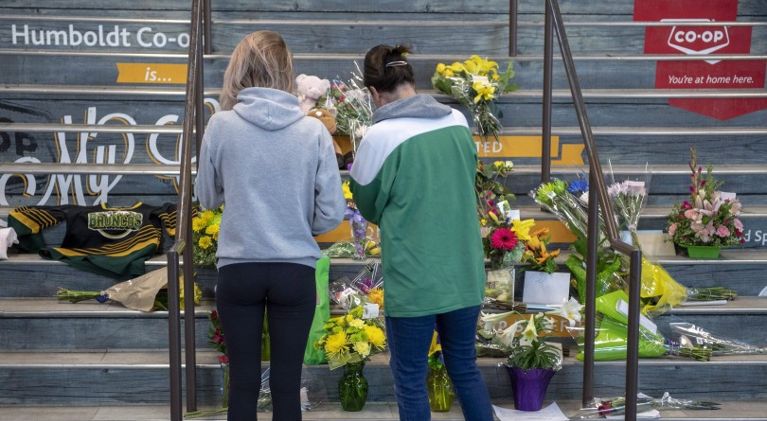 People gather at a memorial set up on the stairs that lead to Elgar Petersen Arena in Humboldt, Sask. on April 7, 2018