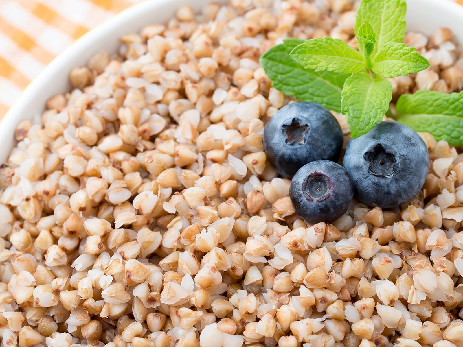 Bowl of cooked buckwheat groats topped with blueberries and mint