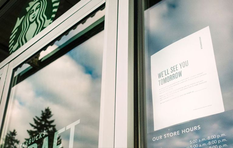 Starbucks door with sign saying "We'll see you tomorrow" to let customers know of closure for anti-bias training