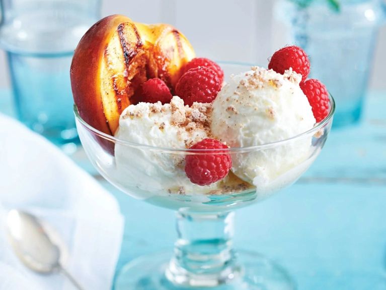 Grilled peach melba with raspberries and vanilla frozen yogurt in a parfait glass