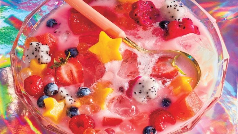 A large glass punch bowl filled with blueberries, raspberries, strawberries, and star-shaped piece of dragonfruit, mango and watermelon for a post on an easy hwachae recipe and the best cooling Summer desserts