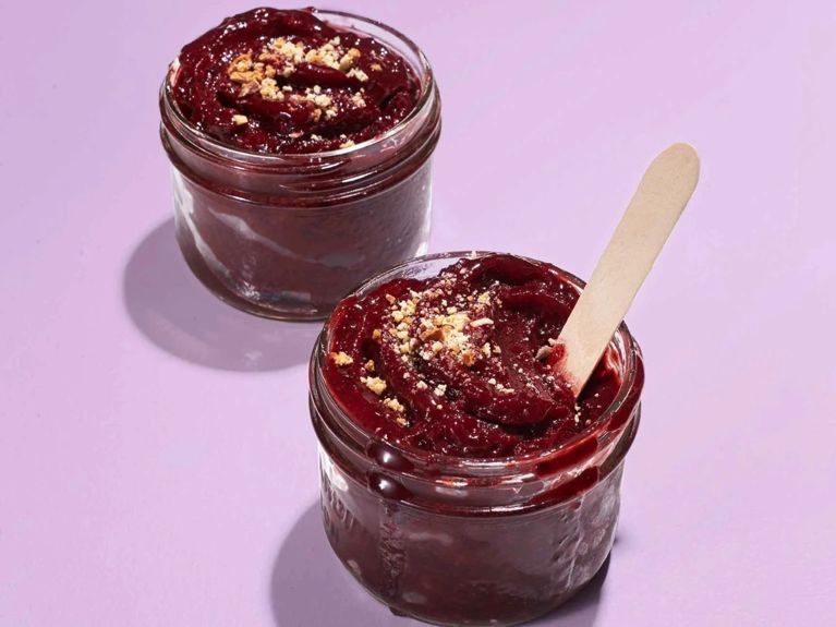 Instant cherry sorbet in a mason jar with a popsicle stick resting in it; the sorbet is made with frozen black cherries; amaretto; and lemon juice for a post on an easy black cherry sorbet recipe