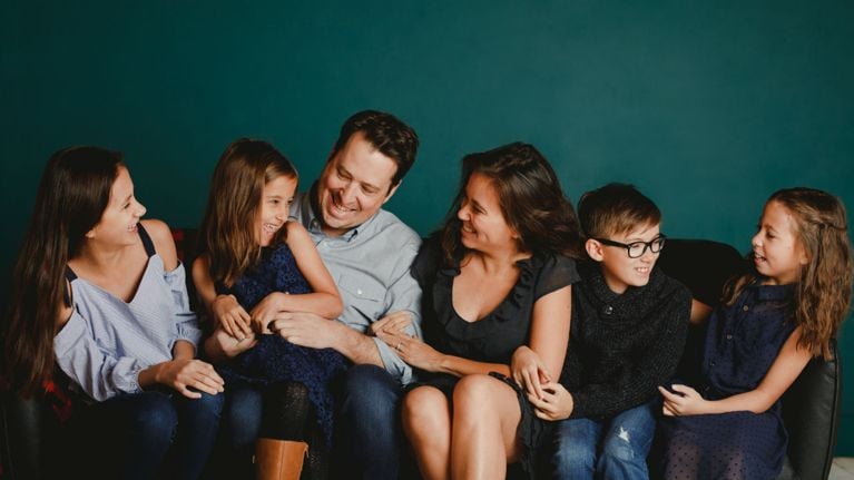 Family of six in shades of blue and black, left to right: daughter, father holding daughter, mother, son, daughter