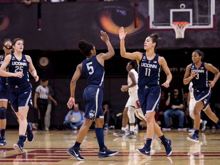 Kia Nurse give a team mate a high five in a navy blue uniform