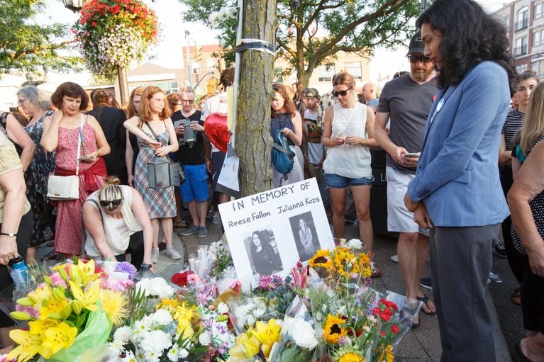 MPP Doly Becum, Scarborough South-West, leaves flowers by a poster of shooting victim Reese Fallon in Alexander the Great Parkette near Danforth Ave. in Greek Town in Toronto on July 25, 2018. The vigil honours the lives affected by the recent tragic shooting by a lone gunman who killed two young women and injured another thirteen people.