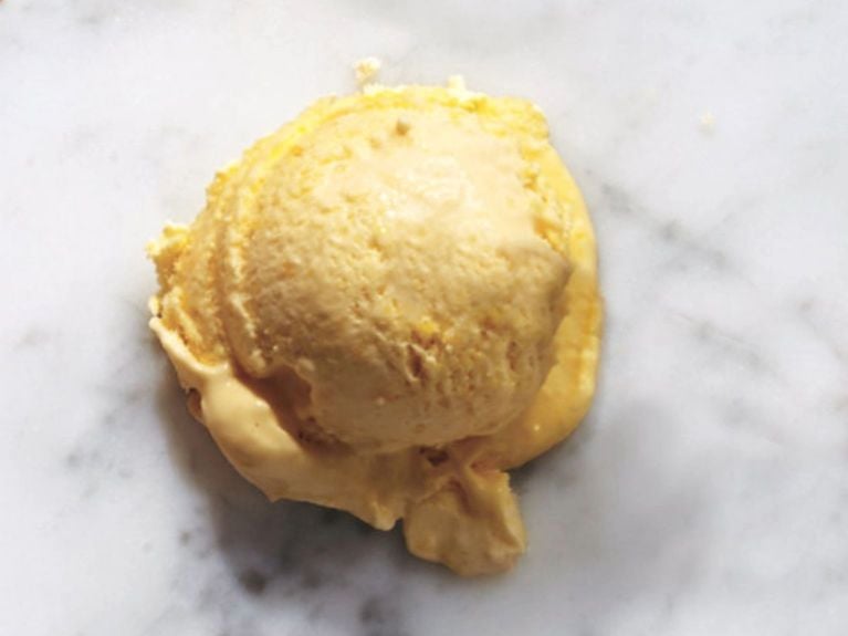 a scoop of mango ice cream on a marble counter top 