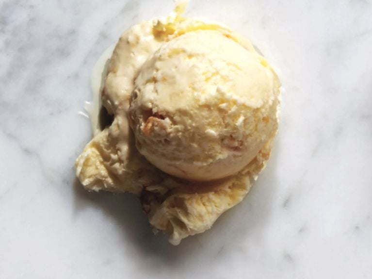 a scoop of sweet corn ice cream on a marble counter top 