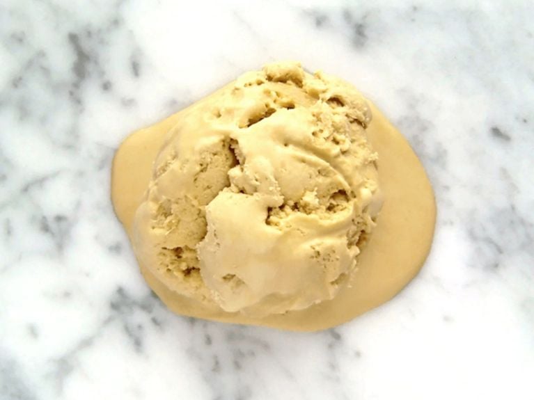 A scoop of molasses ice cream on a marble counter top 