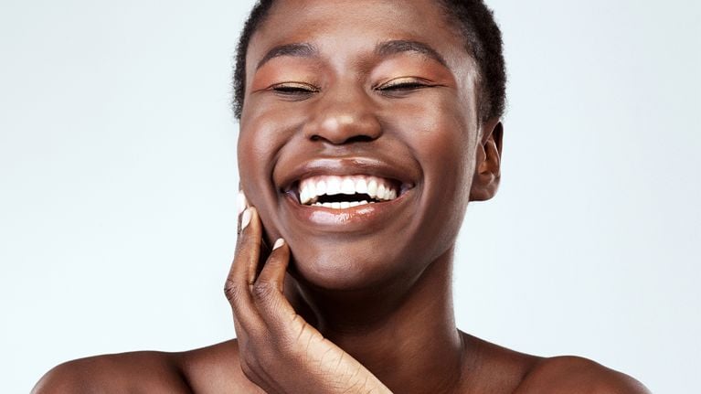 A model with luminous skin against a blue background to illustrate an article about hyaluronic acid skincare.