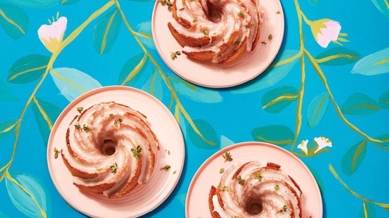 Three mini lemon bundt cakes on pink plates with a floral background