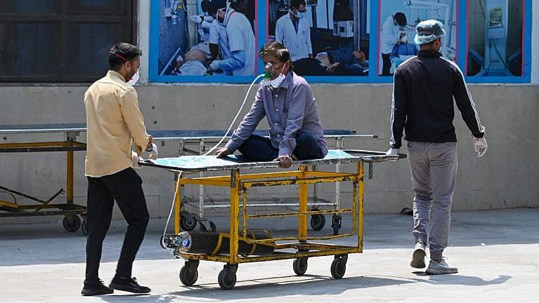 A COVID-19 patient is shifted to a ward after being admitted at the GTB hospital in New Delhi on April 29, 2021. (Photo by Prakash SINGH / AFP via Getty Images)