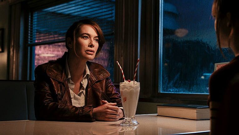 A woman drinks a milkshake in a diner