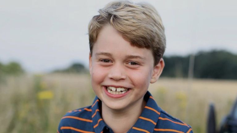 PRince George's 8th birthday portrait, showing the prince in a striped polo smiling against a grassy backdrop