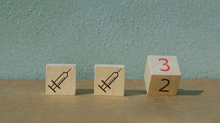 Three wood blocks showing, for the first two, a syringe, and the third, the number two turning to the number 3