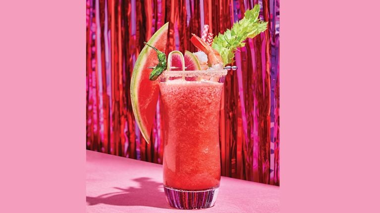 A classic spicy caesar cocktail garnished with a lemon slice and celery stalks on a white background for a post on an easy classic caesar recipe for Canada day