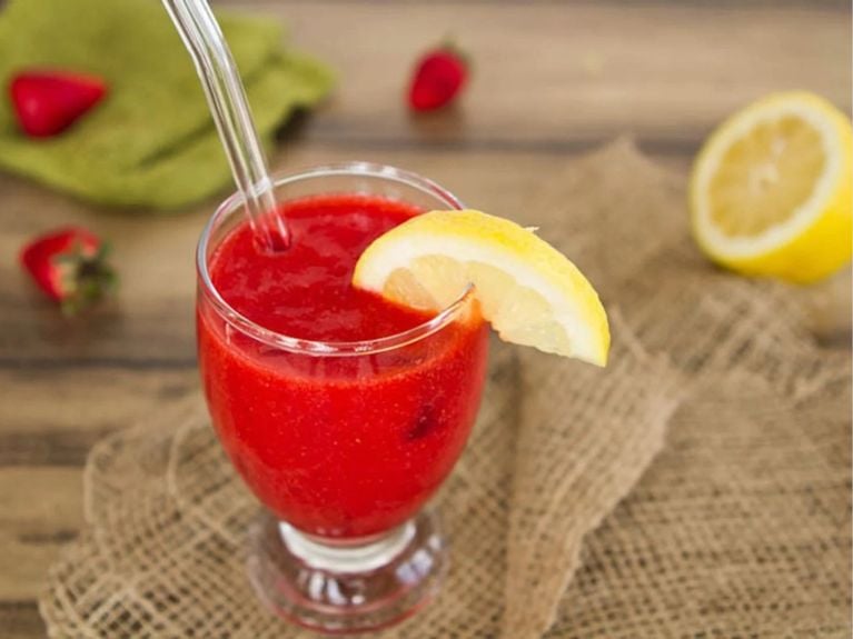 strawberry lemonade ice drink in a glass with a slice of lemon on the rim 