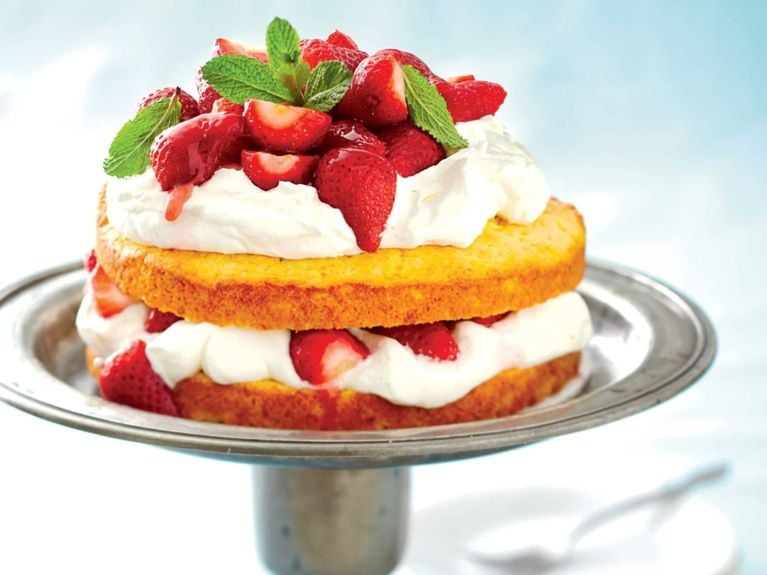 Polenta strawberry shortcake topped with cream and strawberries and fresh mint on a silver serving platter