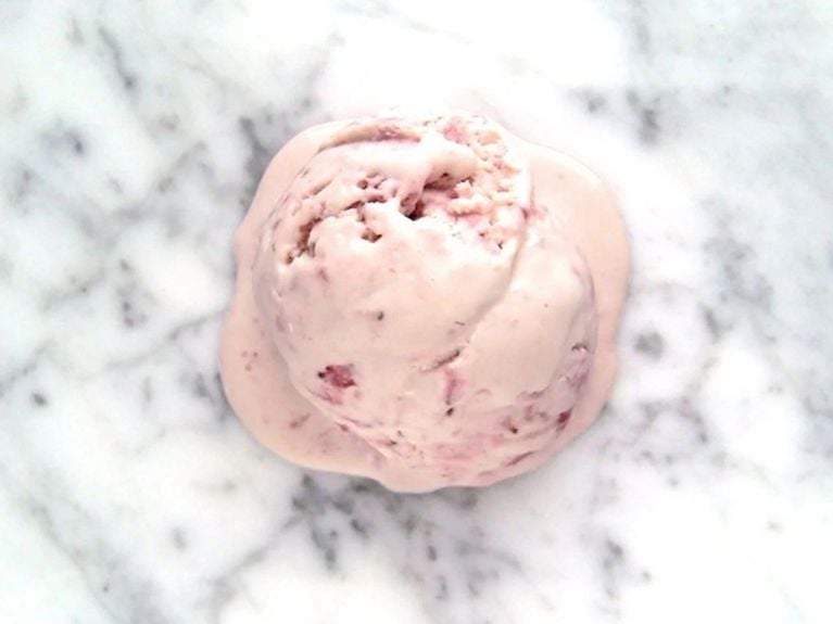 An overhead shot of a scoop of strawberry ice cream melting on the countertop.
