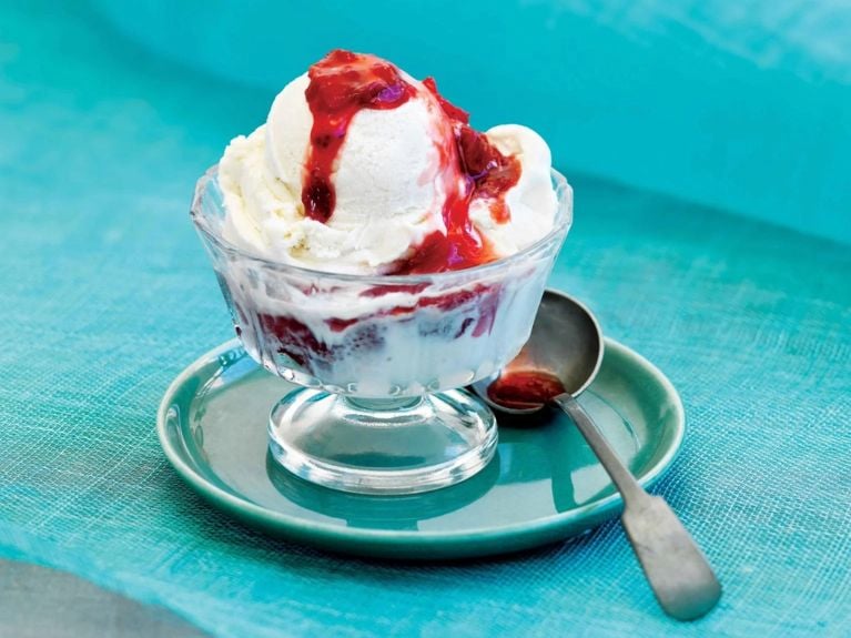 A bowl of ice cream covered with wine-soaked strawberry sauce, made with strawberries; red wine and sugar for a post on an easy wine-soaked strawberry sauce recipe