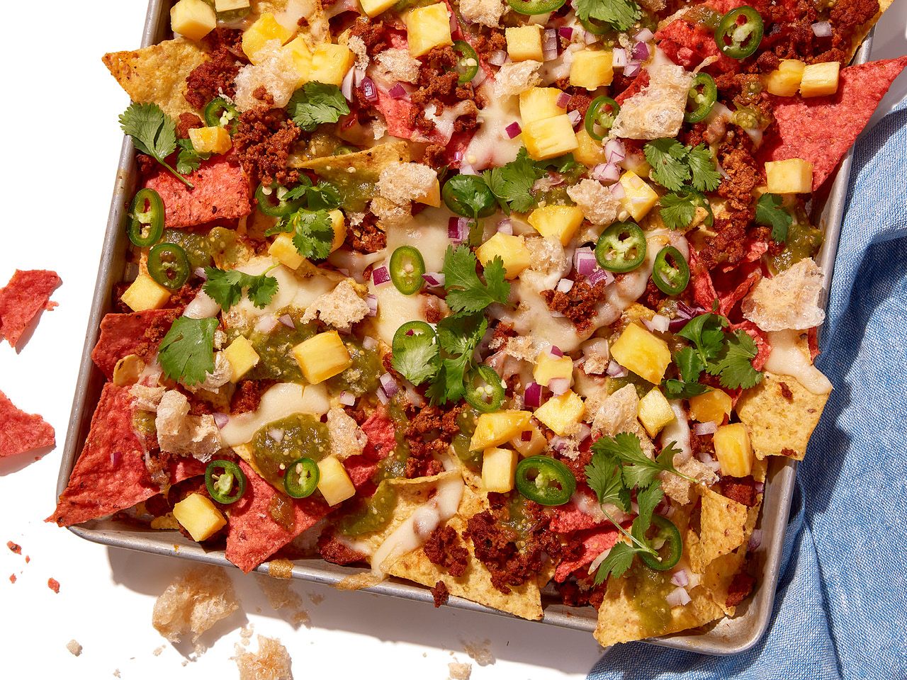 Chorizo and pineapple nachos served on a tray with cilantro and sliced jalapeno