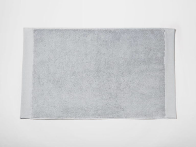 A grey terry cloth Silk & Snow bath mat.