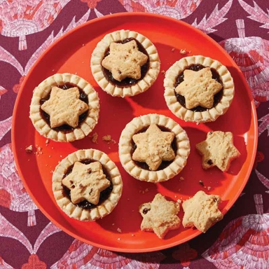 Easy mincemeat tarts, made of store-bought tart shells, mincemeat and star shortbread cookies, on a red plate with the star cookies to the side for a post on an easy shortbread cookie recipe