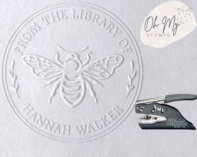 A photo of an embossed stamp on paper, featuring an overlay image of an embosser stamp for a post about the best gifts for book lovers.
