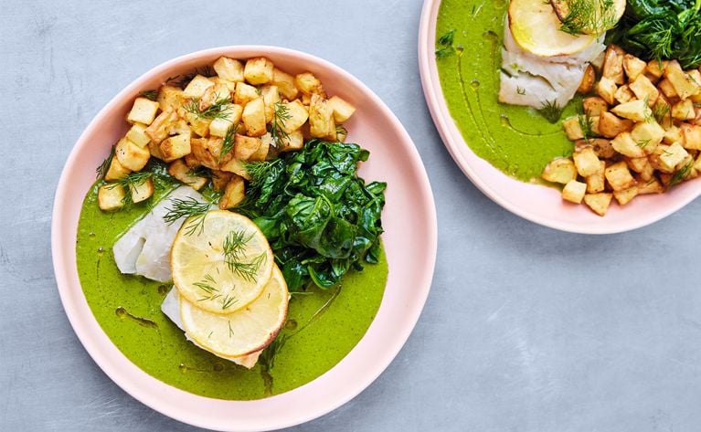 two pink plates with lemon fish potatoes and spinach