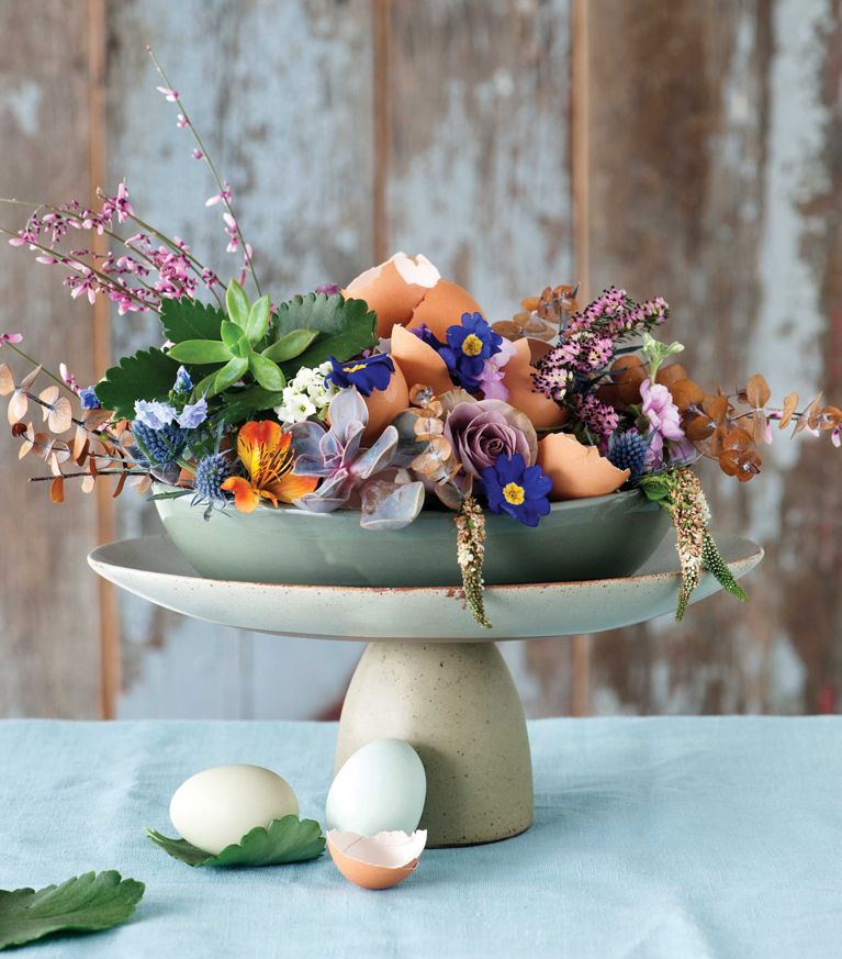 a beautiful flower centrepiece with flowers and eggs and succulents Start by lining a serving dish with green floral foam and adding flowers and succulents. Nestle in eggshell halves, building up the centrepiece as you go. Finish it off with a few branchy stems to add height and visual interest.
