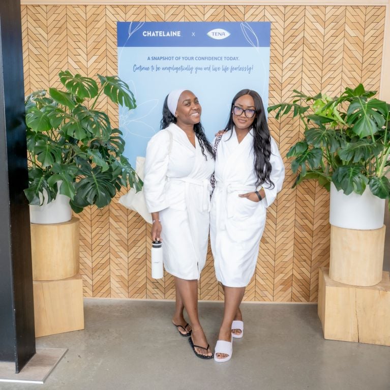 Two women in white robes against a photo wall at the Chatelaine Wellness Retreat.