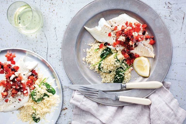 Haddock with tomato relish on a plate next to couscous with spinach for a post on an easy two for one weeknight haddock recipe