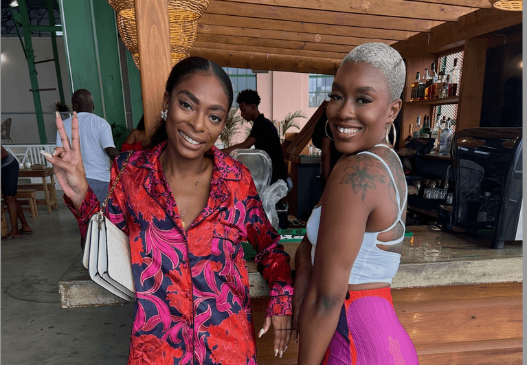 A photo of two women in brightly coloured clothing standing against a bar, used in a piece on long-distance friendship.