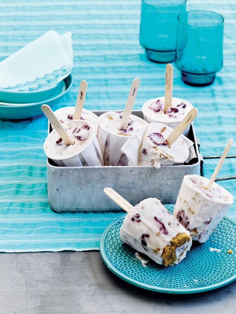 Cherry cheesecake ice cream ice pops formed in Dixie cups with popsicle sticks in a pan after being frozen; the ice pops are made with coarsely chopped graham-crackers; cream; cream cheese; honey; lime juice; cherries for a post on a cherry cheesecake ice cream ice pop recipe