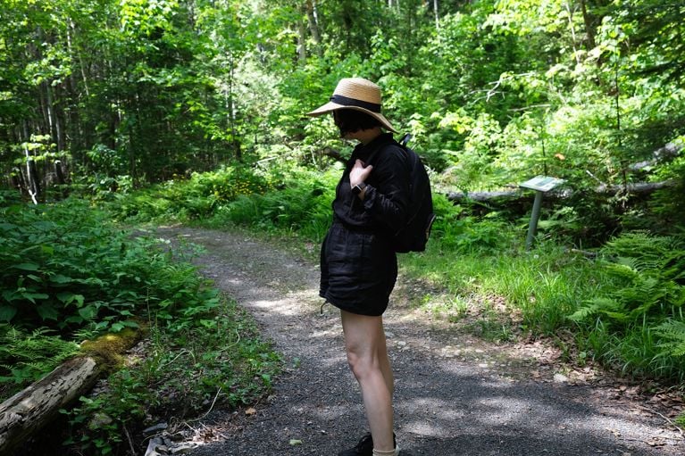 A woman standing on a hiking trail in the woods in Charlevoix, Quebec