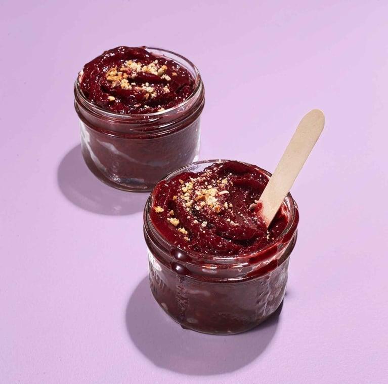 Instant cherry sorbet in a mason jar with a popsicle stick resting in it; the sorbet is made with frozen black cherries; amaretto; and lemon juice for a post on an easy black cherry sorbet recipe
