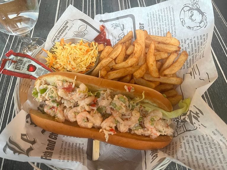 a seafood sandwich on a plate with French fries from Le Saint pub in Baie-Saint-Paul