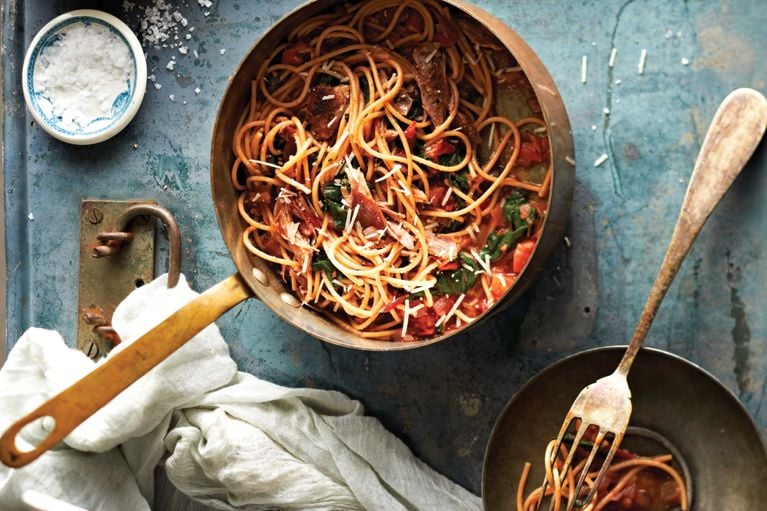 a copper pot filled with Spaghetti with duck confit and chard, made with whole-wheat spaghetti pasta; butter; Swiss chard; duck confit; onion; marjoram; thyme; red wine; chicken broth; tomatoes; parmesan for a post on a Spaghettic with duck confit and Swiss chard recipe