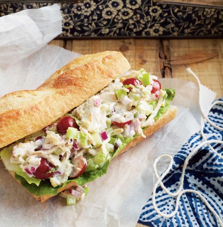 Tarragon-chicken sandwiches with red grapes on a baguette; made with chicken breasts; salt; mayo; fresh tarragon; lemon juice and lemon zest; celery; red seedless grapes; red onion; and romaine lettuce for a post on a tarragon chicken sandwich with red grapes recipe for picnics