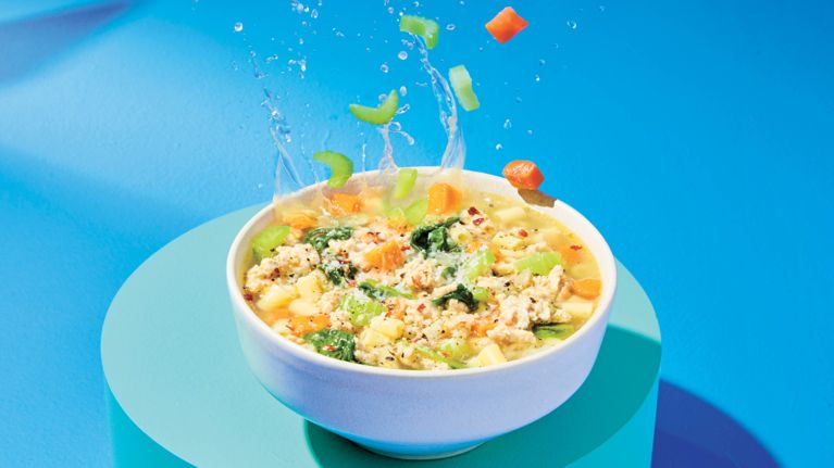 A bowl of noodle soup with chopped vegetables and ground chicken for a story on recipes for ground meat.
