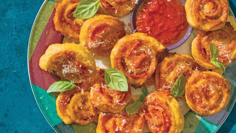 A plate of spiral-shaped pizza rolls made with pepperoni, cheese and puff pastry.