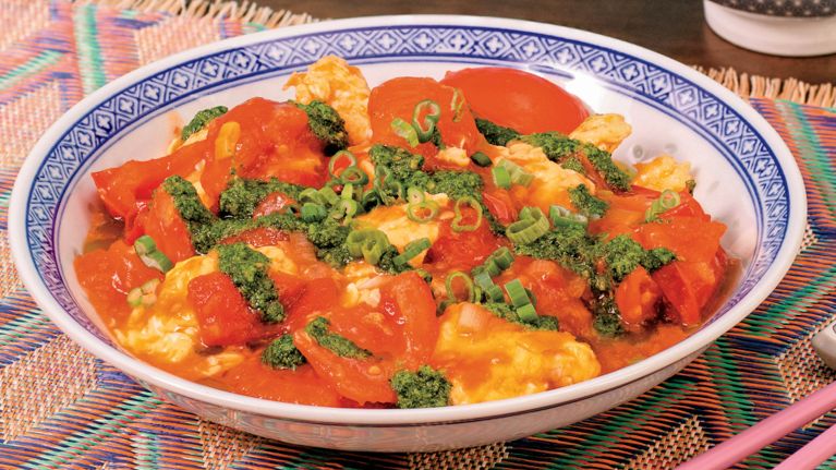 A blue-and-white printed bowl of stir fried tomatoes and scrambled eggs.