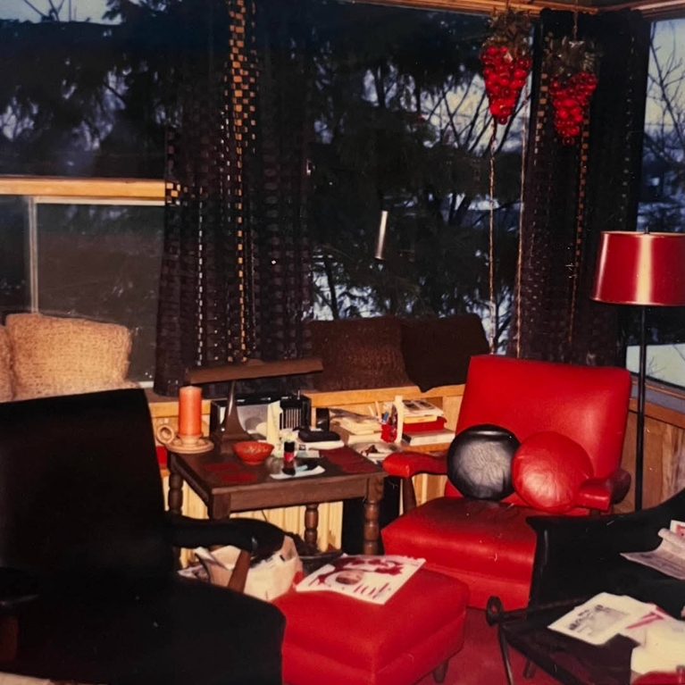 A photo of a living room with a red leather chair and hanging light fixtures in the shape of grapes;