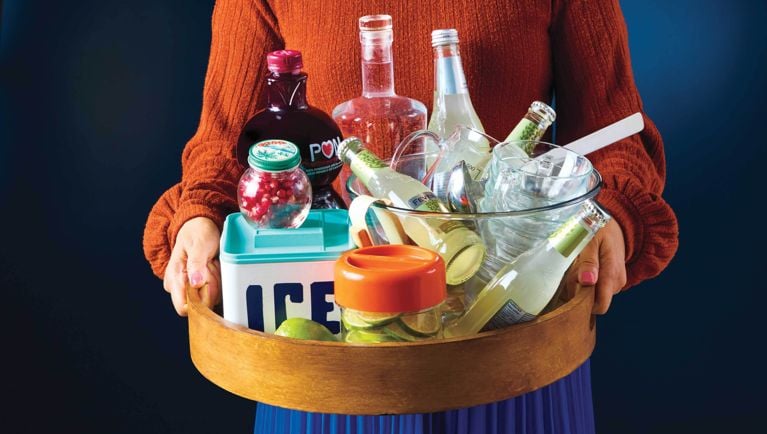 A woman holds a tray of cocktail ingredients