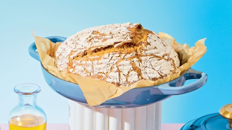 A loaf of no-knead bread in a blue bread oven