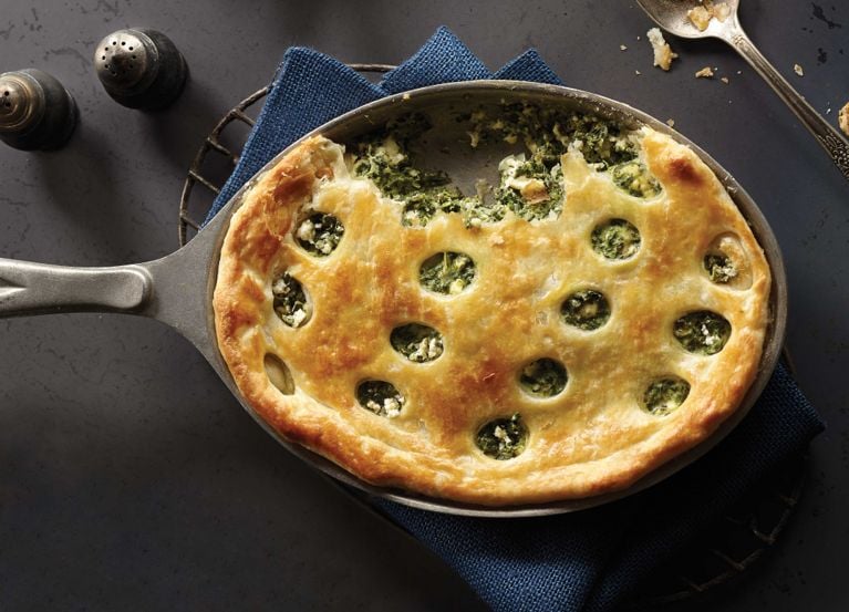 Spinach and feta one-pan pie in a skillet; the pie is made with frozen chopped spinach, thawed; eggs; cream cheese; olive oil; onion; dill; numeg; salt and a 1/2 450-g pkg frozen Tenderflake puff pastry sheets, thawed for a post on an easy one-pan spinach feta pie recipe