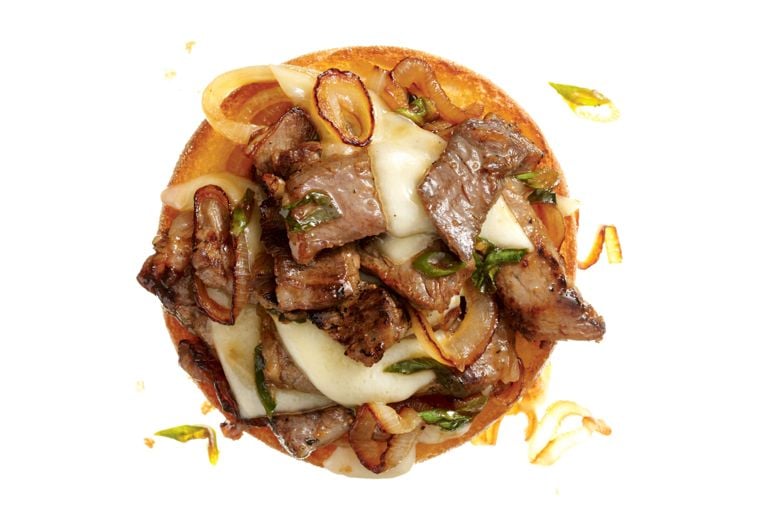 A bulgogi steak and cheese melt with fried onions and swiss cheese on a kaiser for a post on an bulgogi steak and cheese melt recipe
